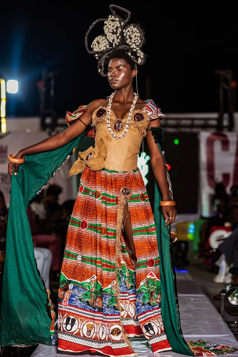 Model in a headdress and printed gown with green cape