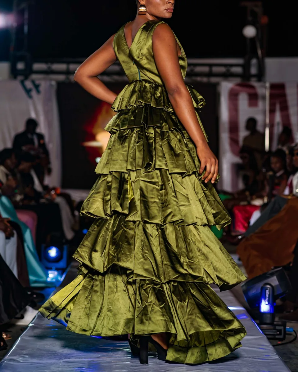 Model in an olive ruffled gown on the runway
