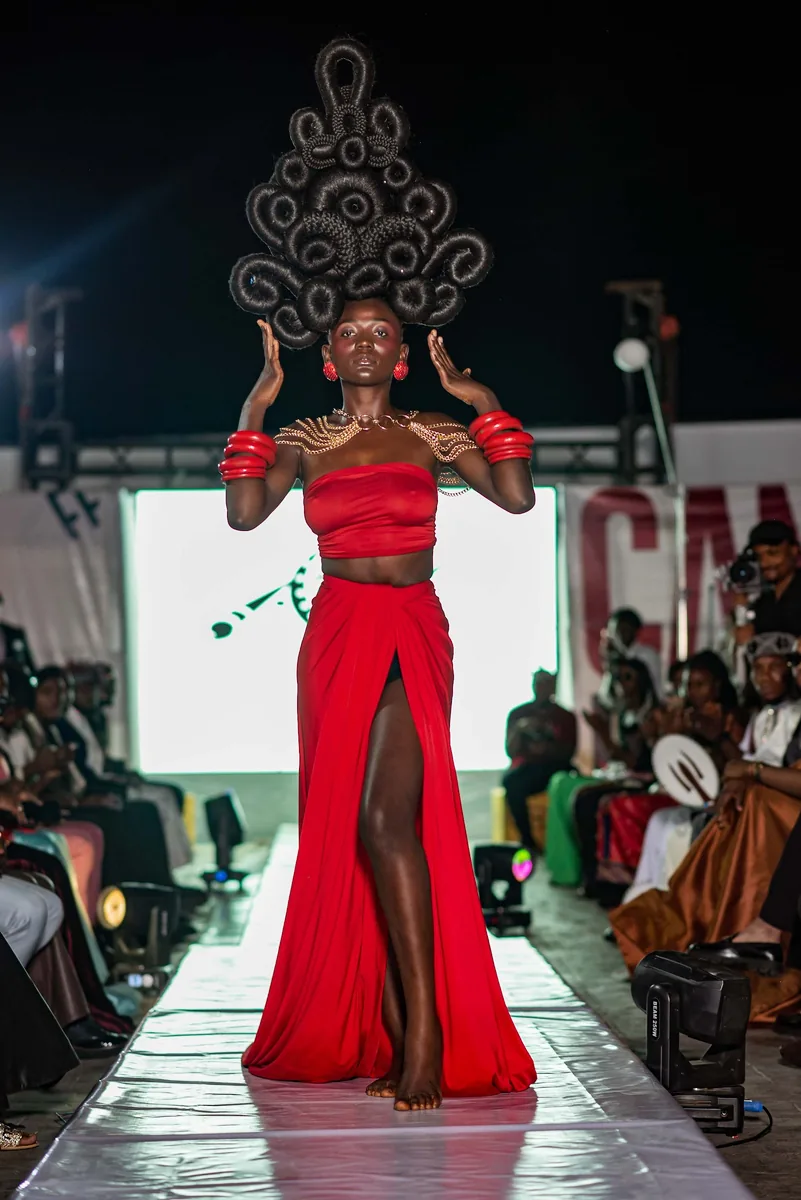 Model in a red gown and sculpted headpiece on the runway