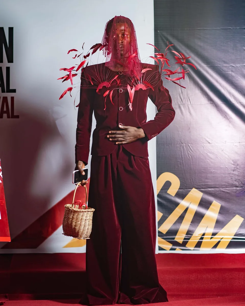 Guest in a burgundy suit and red feather veil