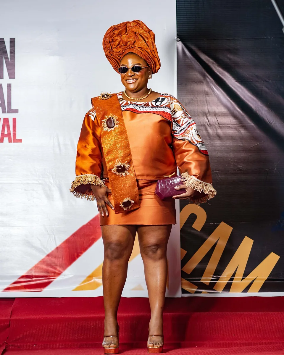 Guest in an orange gele and ruffled dress
