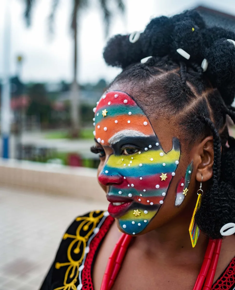 Model with rainbow face paint and beaded braids