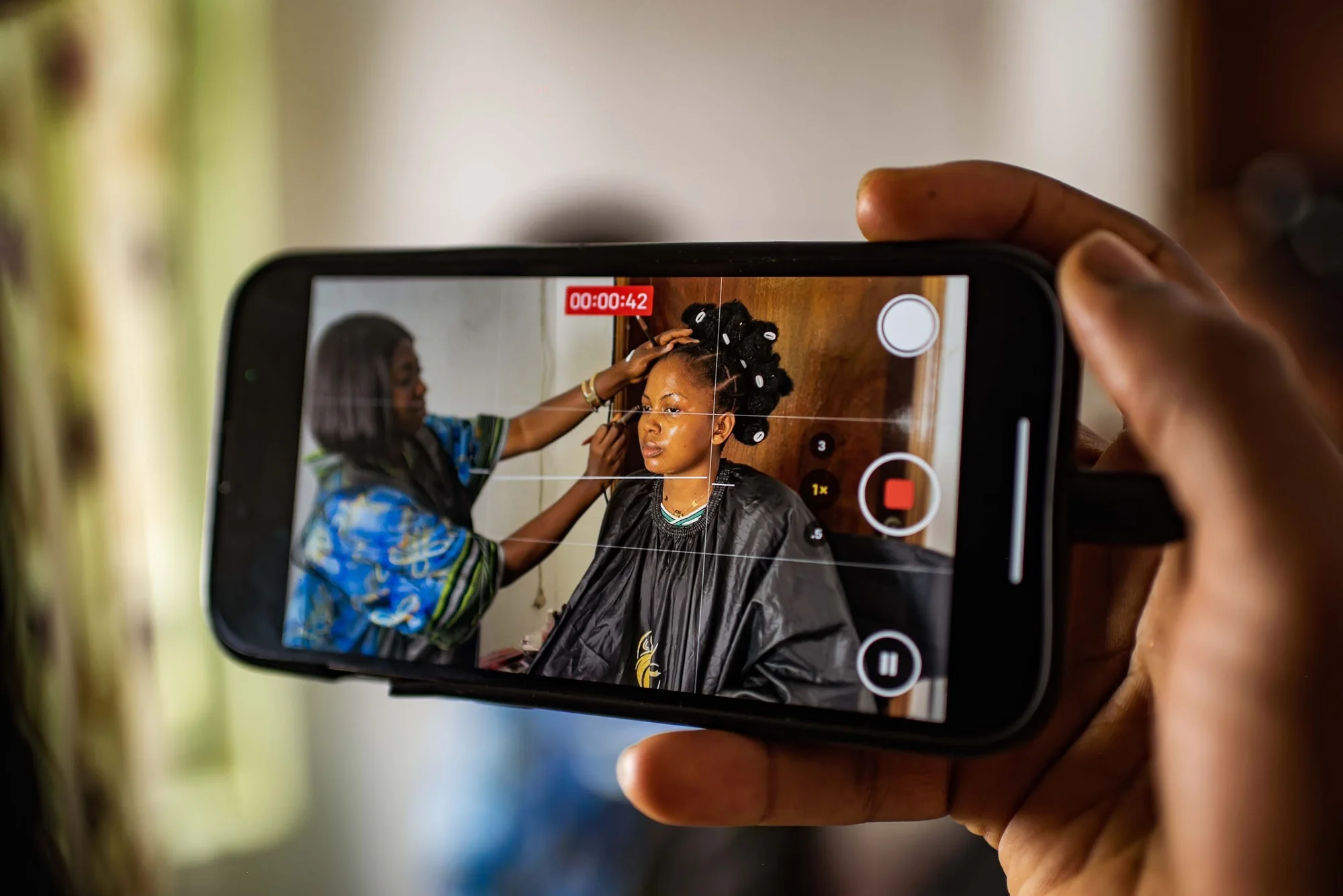 A phone filming a model in the makeup chair backstage