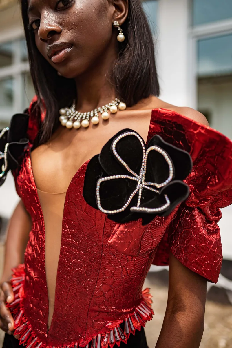 Model in a red corset dress with a black rosette
